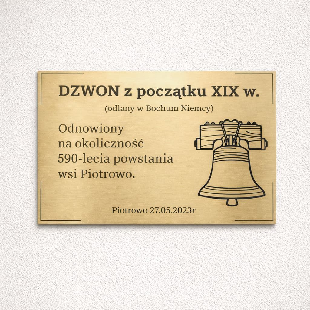 Złota tabliczka pamiątkowa z czarnym grawerem przy dzwonie odnowionym na 590-lecie wsi