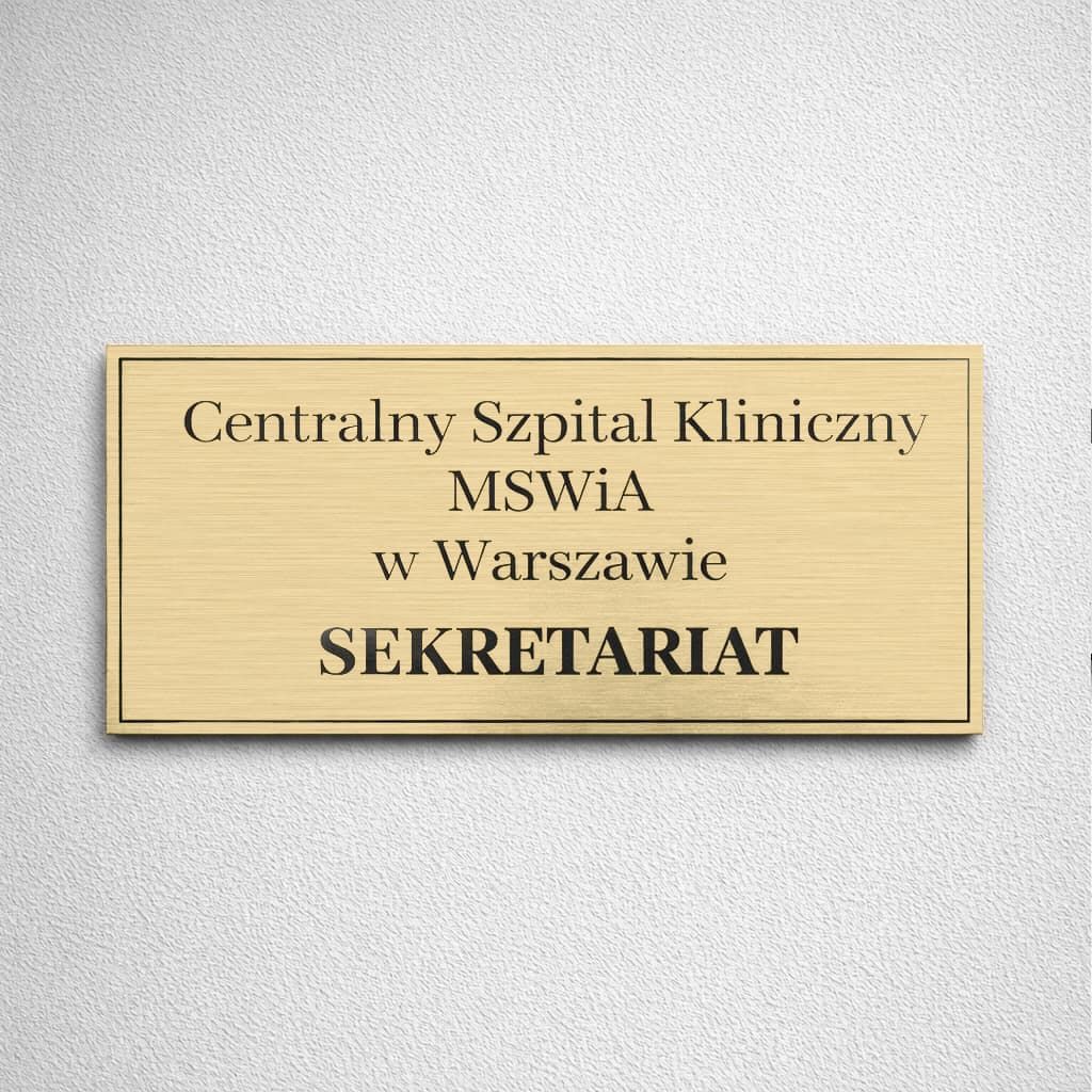 Złota tabliczka na drzwi gabinetu z nazwą szpitala i czarnym grawerem