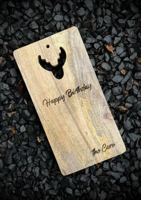 Grawerowanie prezentów na drewnianej desce z wyciętym kształtem poroża i napisem Happy Birthday.