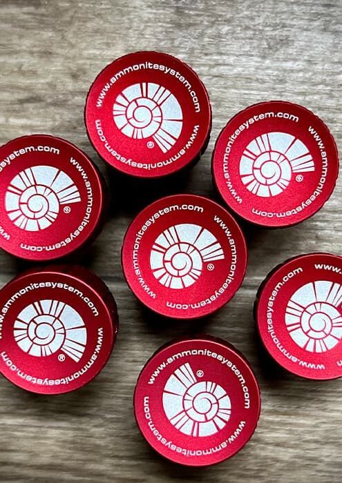 Precyzyjne znakowanie laserowe na czerwonych, aluminiowych okrągłych tagach z logo Ammonite System.