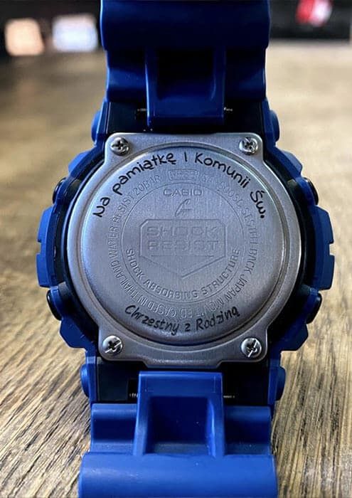 Dekiel niebieskiego zegarka Casio G-Shock z grawerem „Na pamiątkę I Komunii Św.” od chrzestnego z rodziną