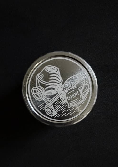 Precyzyjne grawerowanie prezentów na aluminiowym wieczku słoika z grafiką betoniarki.