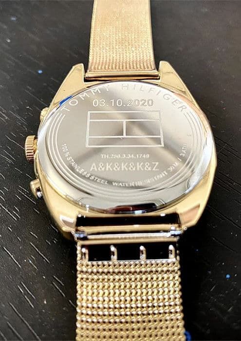 Dekiel złotego zegarka Tommy Hilfiger z datą i inicjałami członków rodziny