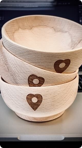 Grawerowanie prezentów na jasnych drewnianych miseczkach z wypalonym motywem serca.