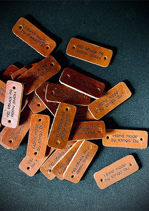 Grawerowanie laserowe dla firm – personalizowane metki produktowe z logo "Hand made by Kinga".
